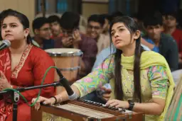 Musicians leading the kirtan with a harmonium and microphones
